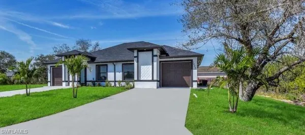 a front view of a house with a yard and trees