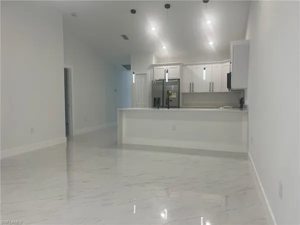 a room with kitchen island a flat screen tv and refrigerator