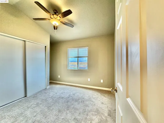 an empty room with a window and a ceiling fan