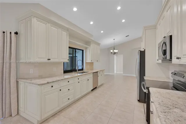 a large white kitchen with a sink a refrigerator and window
