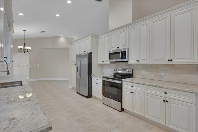 a kitchen with granite countertop white cabinets and stainless steel appliances