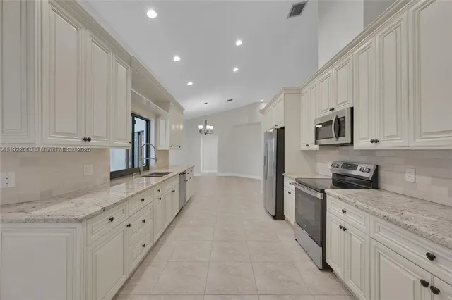 a large kitchen with stainless steel appliances granite countertop a sink and dishwasher a stove top oven with white cabinets