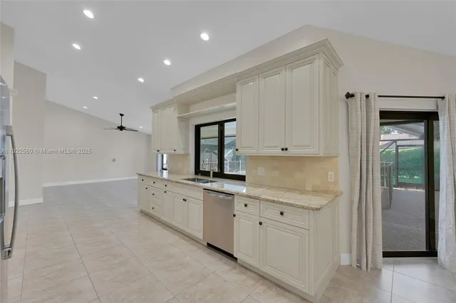 a large white kitchen with stainless steel appliances granite countertop a refrigerator and a stove top oven