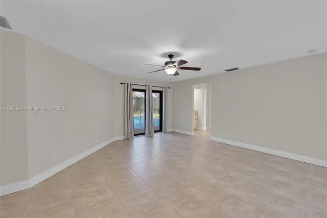 a view of an empty room with a chandelier fan