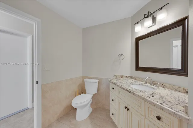 a bathroom with a toilet sink double vanity and mirror