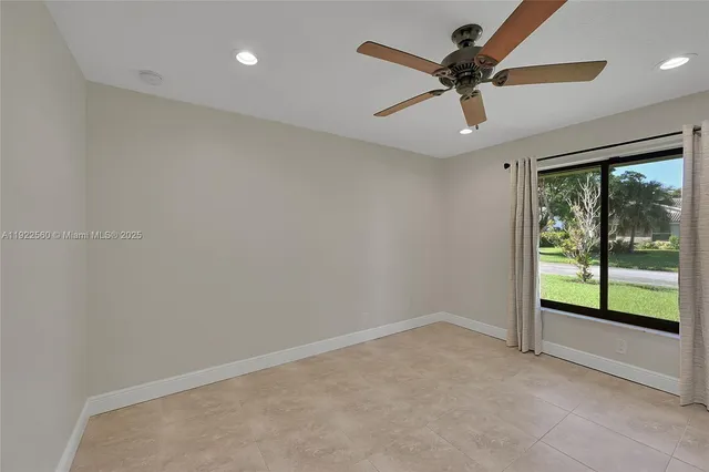 an empty room with a ceiling fan and windows