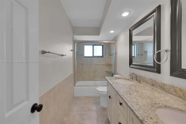 a bathroom with a granite countertop sink a toilet and shower