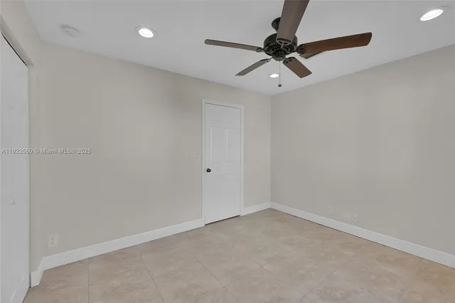 an empty room with a ceiling fan and window