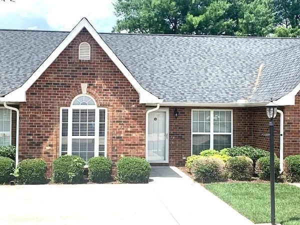 a view of a brick house with large windows and a yard