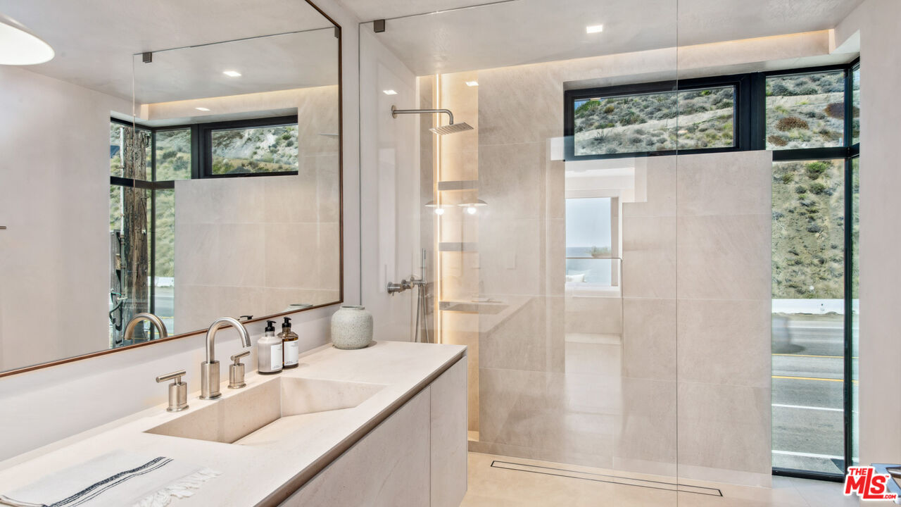 18954 Pacific Coast Highway Malibu, CA 90265 - Photo 35 of 70 a bathroom with a granite countertop sink a shower and a mirror