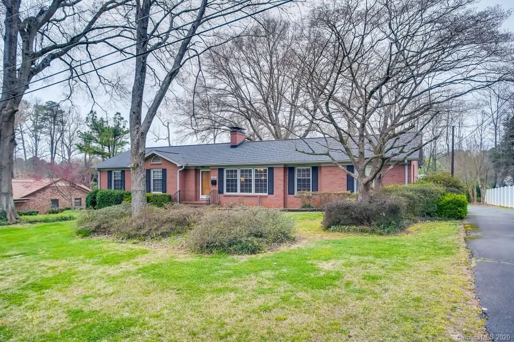 4921 Cheviot Road Charlotte, NC 28269 - Photo 2 of 28 a view of a yard in front of a brick house with large windows