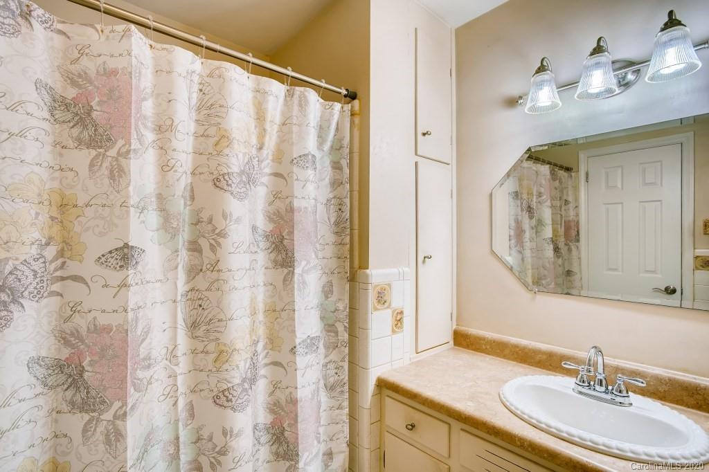 4921 Cheviot Road Charlotte, NC 28269 - Photo 22 of 28 a bathroom with a granite countertop sink a mirror a vanity and a shower