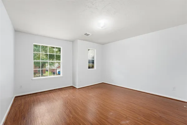 an empty room with wooden floor and windows