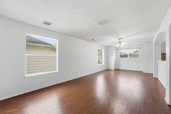an empty room with wooden floor and windows