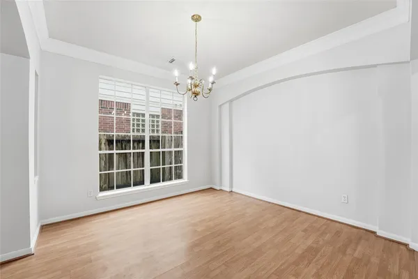 a view of an empty room with a window and hardwood floor