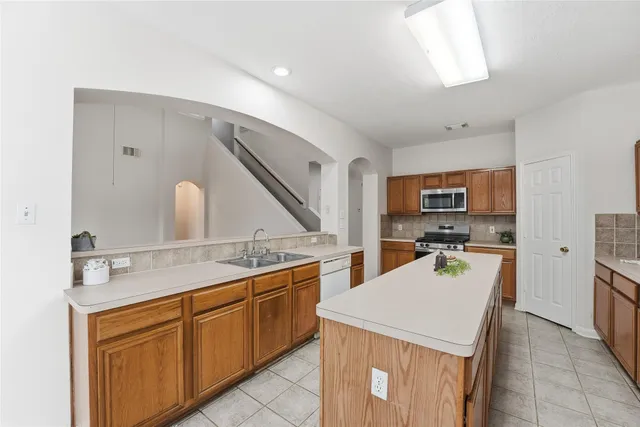 a large kitchen with kitchen island a sink stainless steel appliances and cabinets