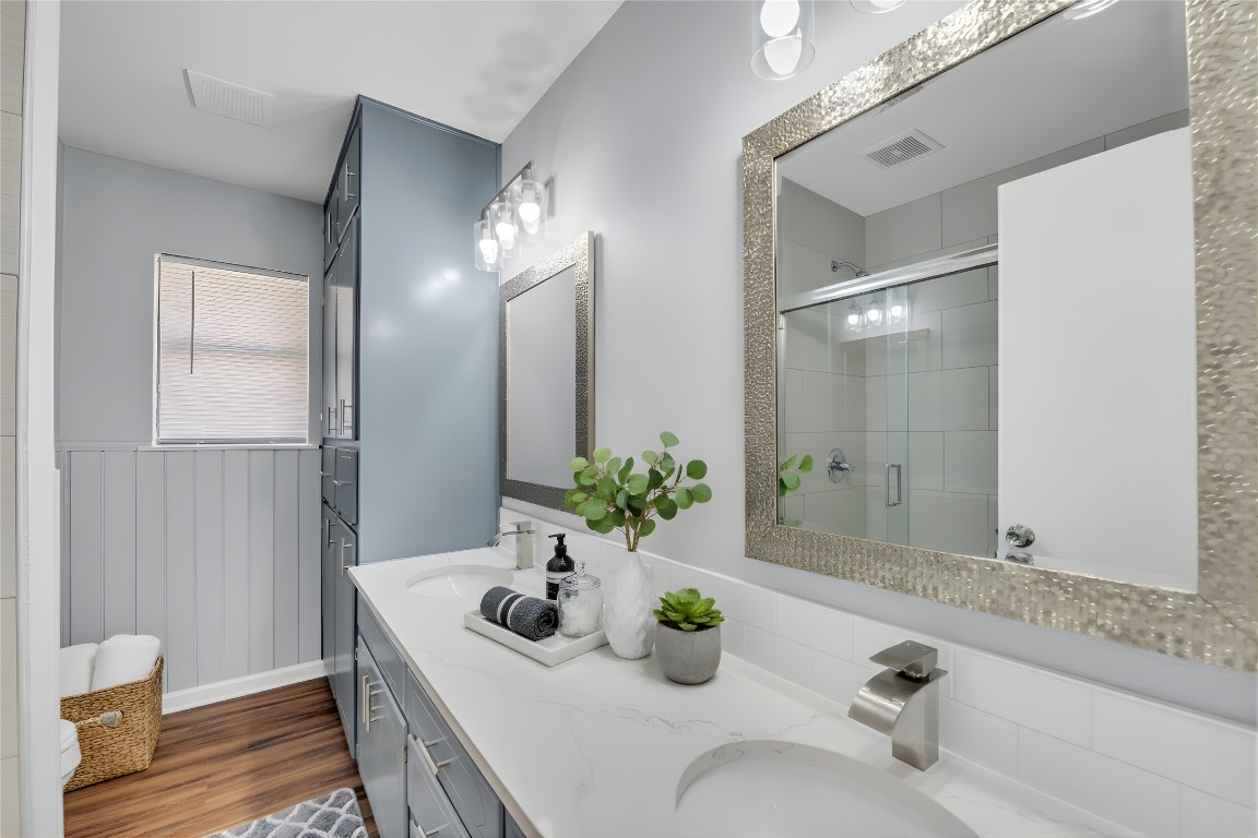 310 Hruskaville Road Temple, TX 76501 - Photo 16 of 21 Bathroom with double vanity, a stall shower, dark wood-type flooring, and a wainscoted wall