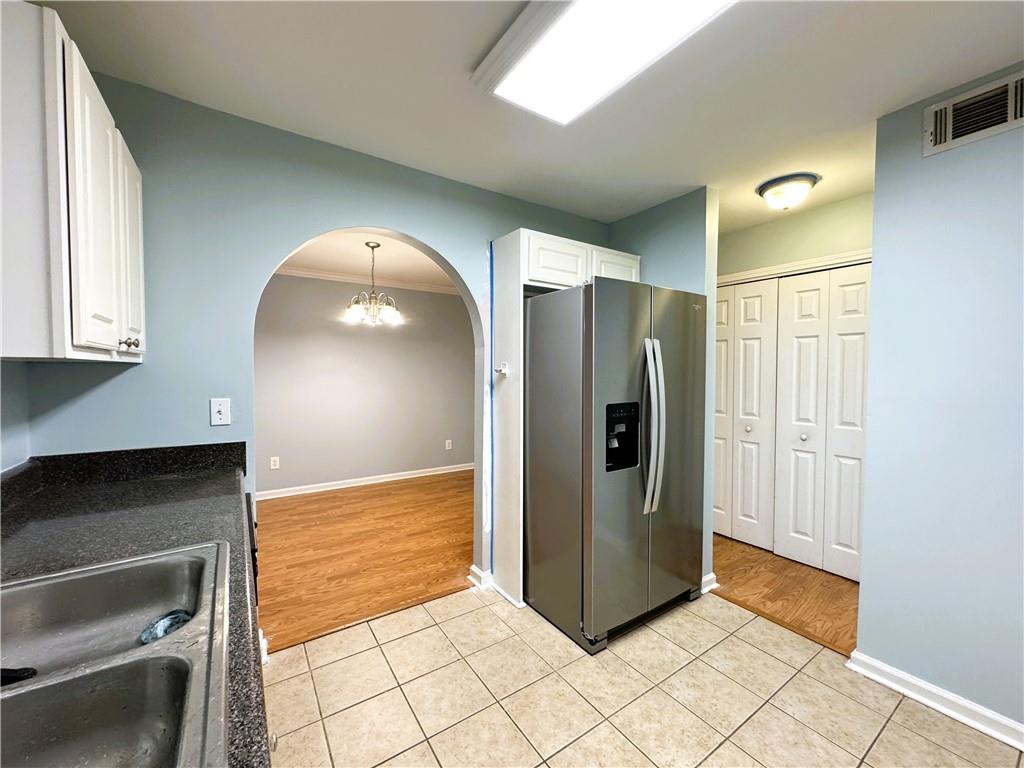 112 Summer Place Northwest Norcross, GA 30071 - Photo 8 of 24 a view of a refrigerator in kitchen and an empty room in wooden floor