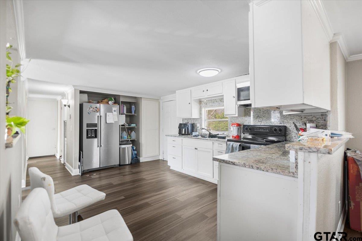 5950-c R 486 C R 486 Tyler, TX 75706 - Photo 9 of 19 a kitchen with stainless steel appliances granite countertop a refrigerator a stove a sink dishwasher and white cabinets with wooden floor