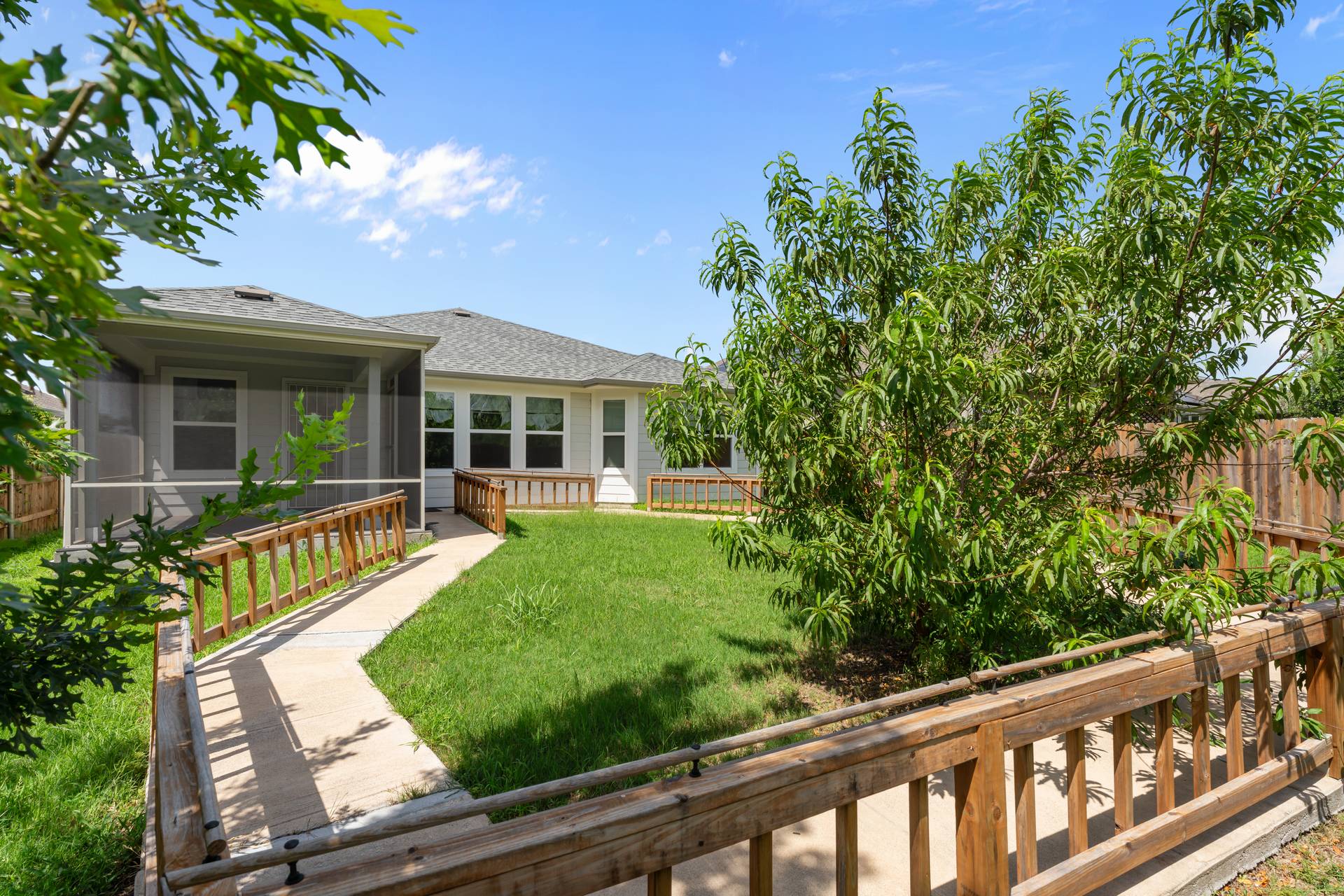 16512 Enamorado Road Manor, TX 78653 - Photo 12 of 31 A well-kept yard extends from the home's rear, featuring a walkway, a screened porch, and a lush privacy fence.