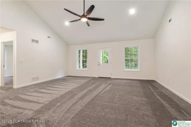 an empty room with windows and ceiling fan