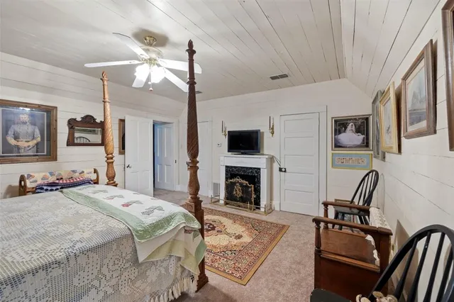 a spacious bedroom with a bed a fireplace and a flat tv screen