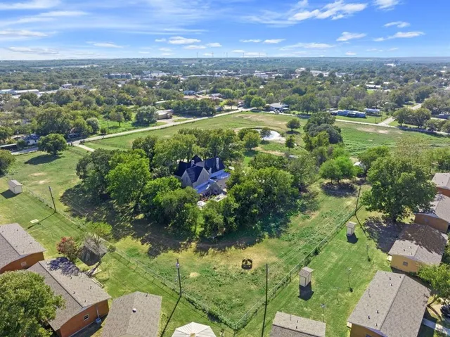 an aerial view of residential houses with outdoor space and trees