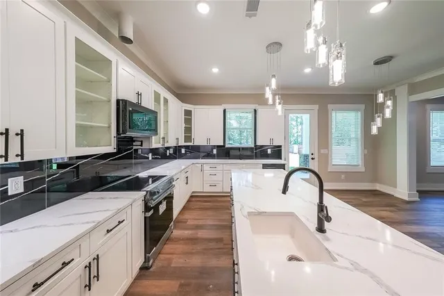a large open kitchen with a large counter top a sink stainless steel appliances and cabinets