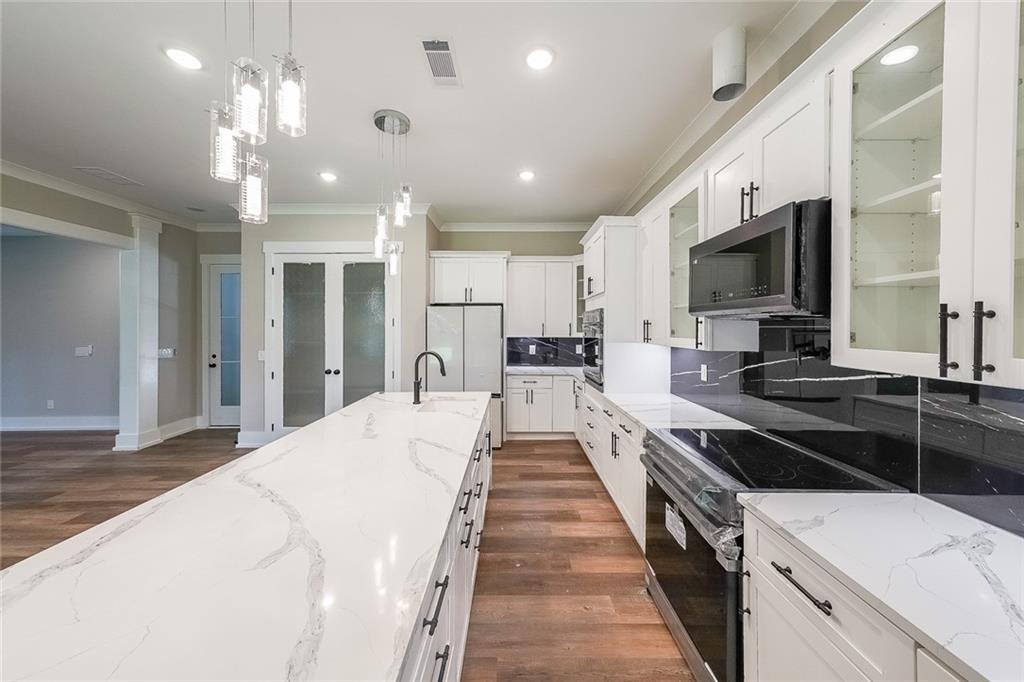 1360 Dickens Road Northwest Lilburn, GA 30047 - Photo 13 of 45 a large kitchen with kitchen island a large counter space a sink appliances and cabinets