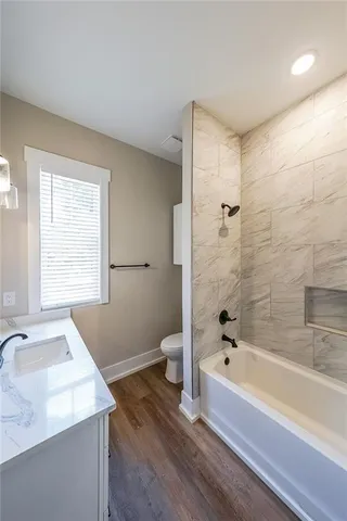 a bathroom with a granite countertop sink a toilet and bathtub