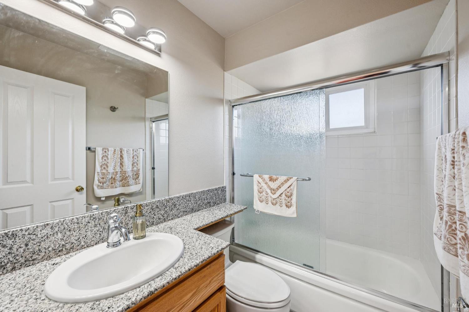 99 San Benito Way Novato, CA 94945 - Photo 20 of 30 a bathroom with a granite countertop sink toilet a mirror a vanity and shower