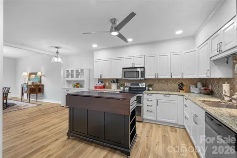 a kitchen with stainless steel appliances granite countertop a stove top oven a sink dishwasher and a refrigerator with wooden floor