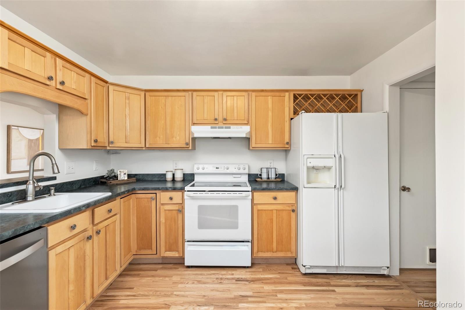 5520 East Bails Drive Denver, CO 80222 - Photo 9 of 38 a kitchen with stainless steel appliances granite countertop a stove a sink dishwasher and a refrigerator with wooden cabinets