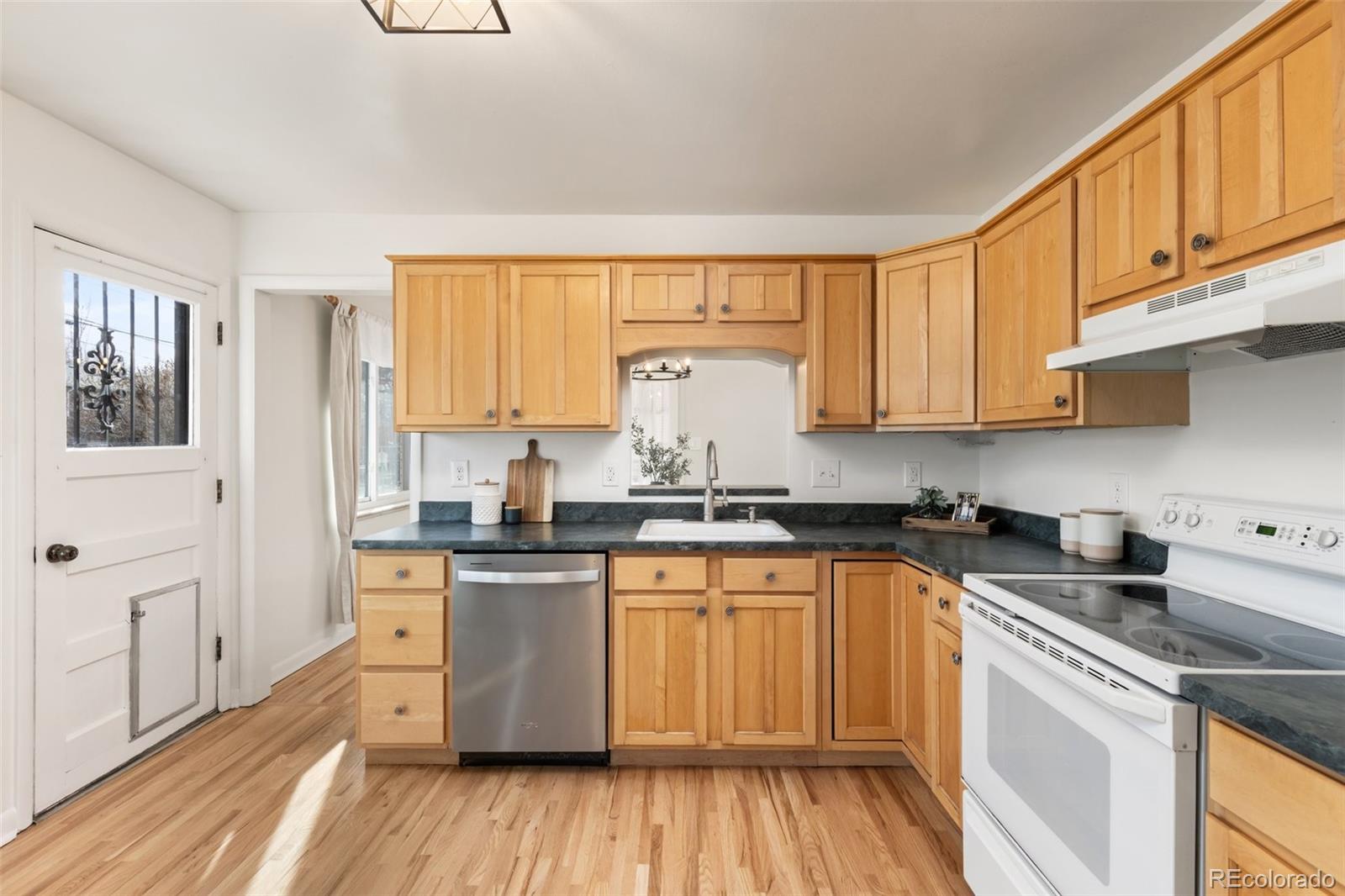 5520 East Bails Drive Denver, CO 80222 - Photo 10 of 38 a kitchen with stainless steel appliances granite countertop a stove a sink dishwasher and white cabinets with wooden floor