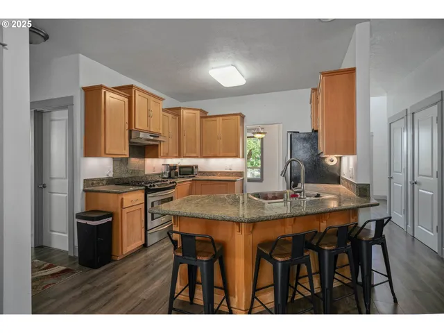 a kitchen with stainless steel appliances granite countertop a sink a stove a refrigerator with a dining table and chairs