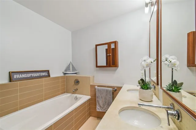 a bathroom with a tub a sink and mirror