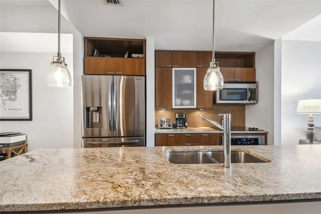 a kitchen with kitchen island granite countertop a refrigerator and a sink