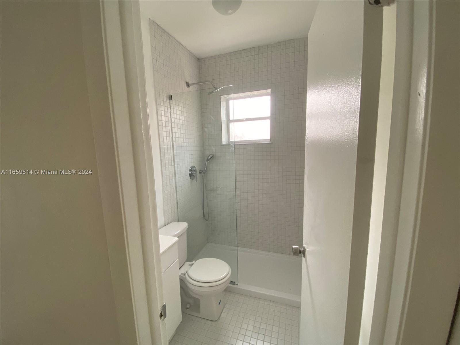 1043 Northwest 2nd Street, Unit 16 Miami, FL 33128 - Photo 13 of 17 a bathroom with a toilet a sink and shower