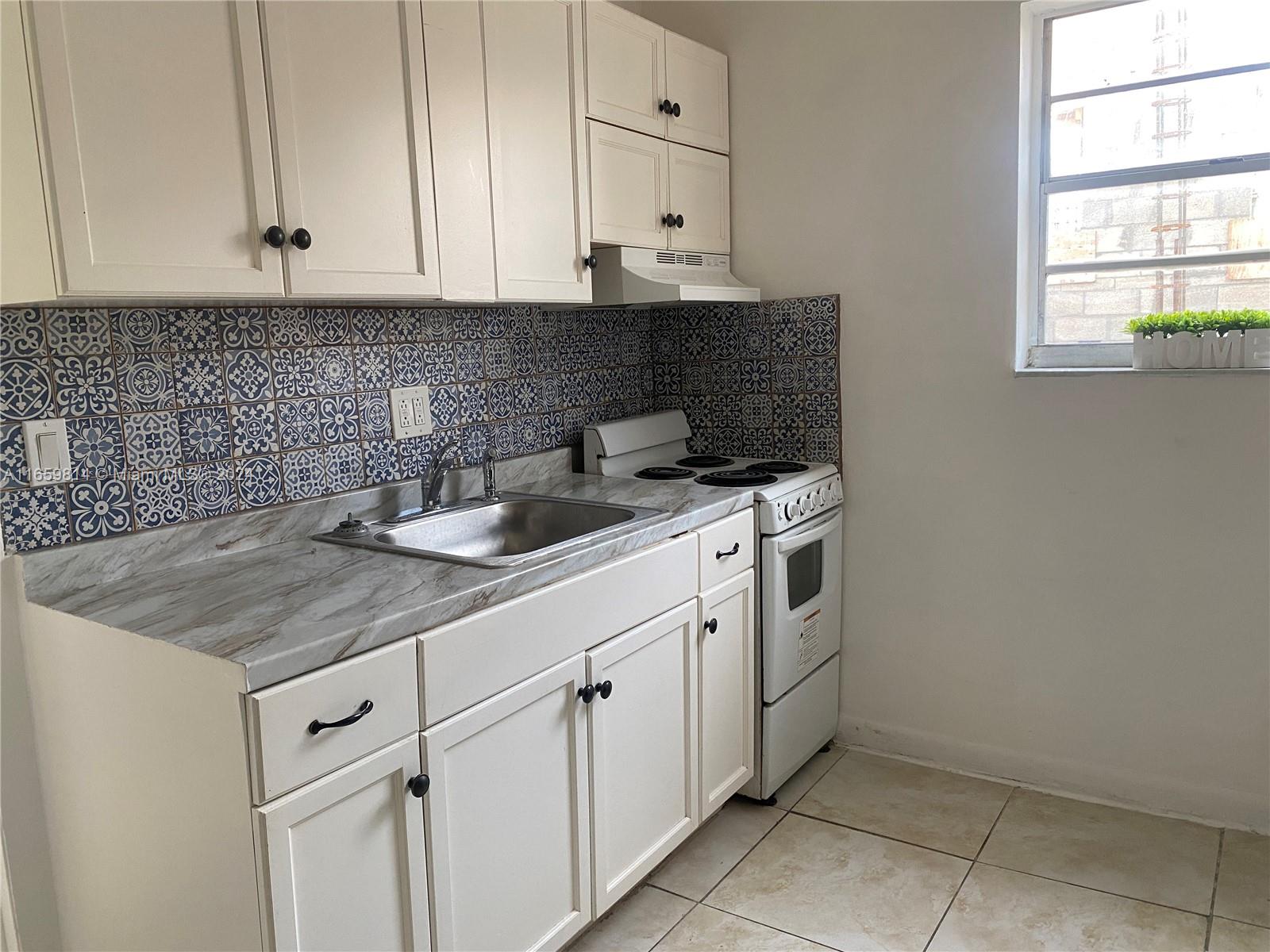 1043 Northwest 2nd Street, Unit 16 Miami, FL 33128 - Photo 3 of 17 a kitchen with white cabinets and white appliances