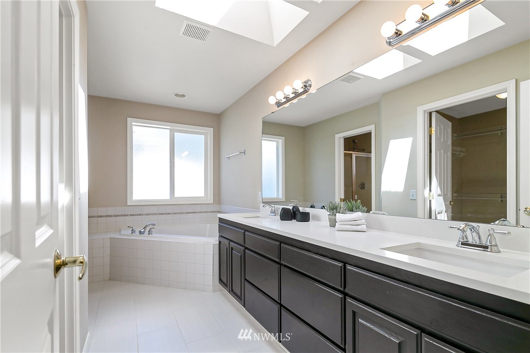 1127 185th Place Southeast Bothell, WA 98012 - Photo 18 of 25 a bathroom with a double vanity sink a mirror and a bathtub