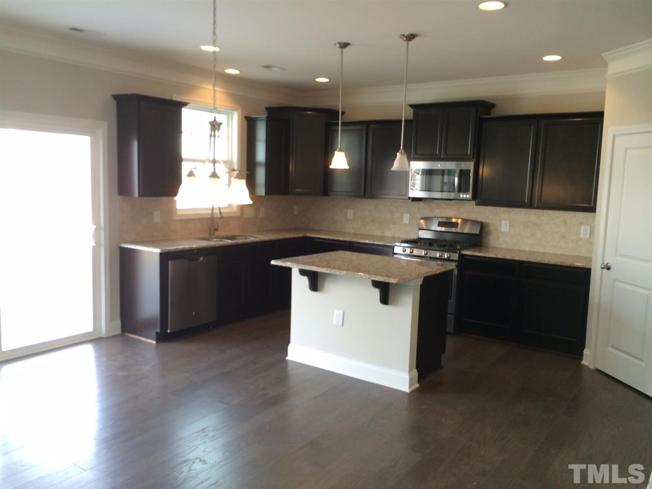 7621 Channery Way Raleigh, NC 27616 - Photo 6 of 25 staggered cabinets with crown on cabinets, granite counter tops with island bar top keep this kitchen very modern