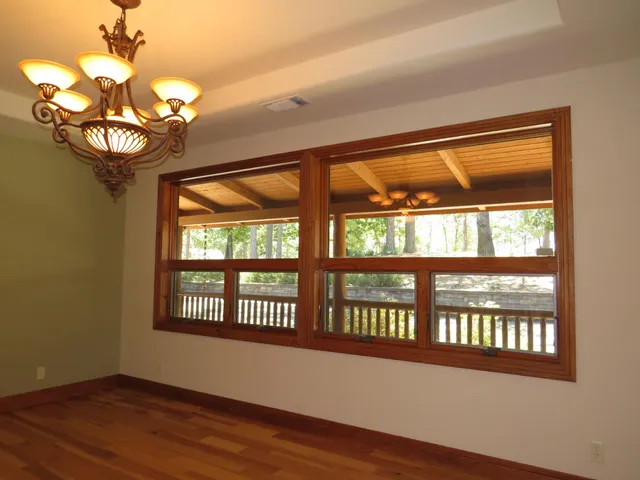 a view of a hallway with wooden floor and a bathroom