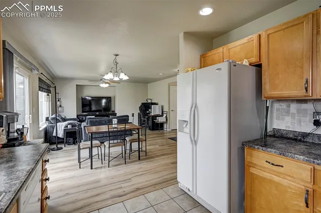 a kitchen with stainless steel appliances granite countertop a refrigerator a stove top oven a dining table and chairs with wooden floor