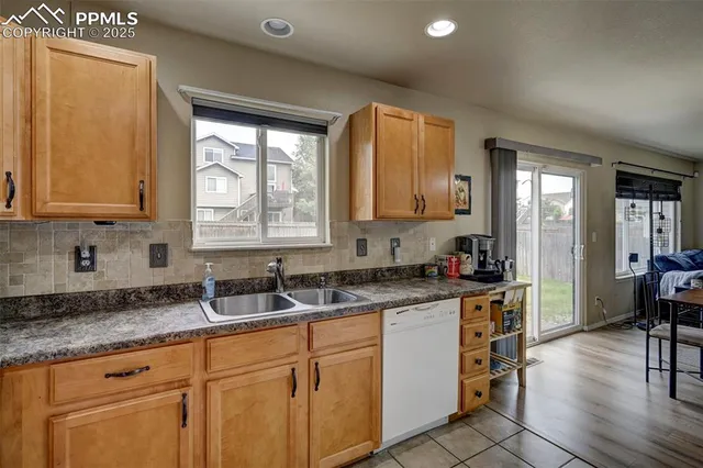 a kitchen with granite countertop a sink cabinets stainless steel appliances and a window