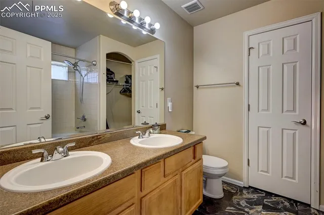 a bathroom with a granite countertop double vanity sink a mirror and a toilet