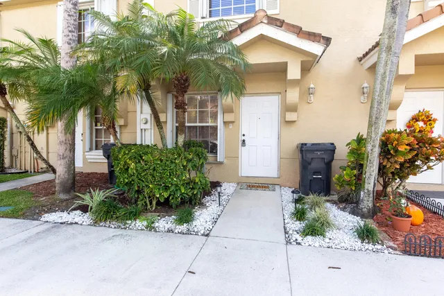 front view of a house with potted plants and a palm trees
