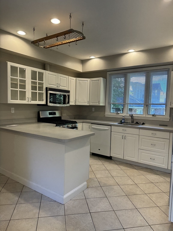 62 Crosby Road, Unit 1 Newton, MA 02467 - Photo 3 of 12 a kitchen with kitchen island granite countertop a stove sink microwave and cabinets