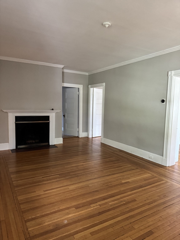 62 Crosby Road, Unit 1 Newton, MA 02467 - Photo 7 of 12 an empty room with wooden floor and fireplace