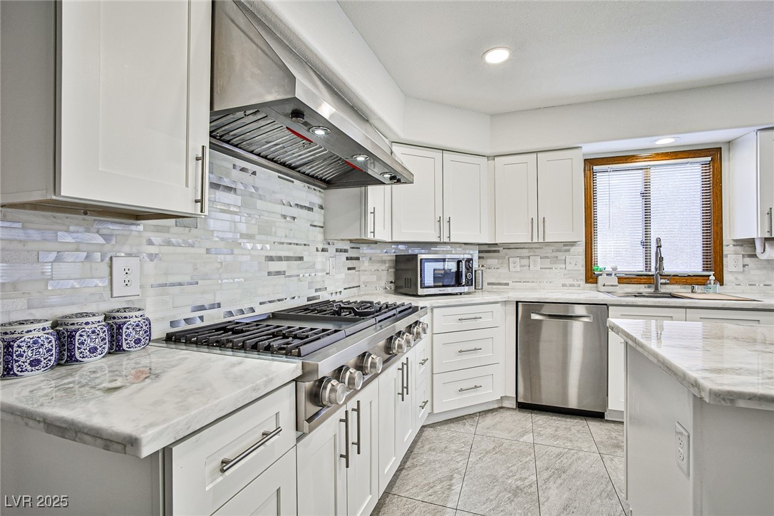 7772 Boca Raton Drive Las Vegas, NV 89113 - Photo 11 of 40 Kitchen with backsplash, light stone countertops, ventilation hood, stainless steel appliances, and white cabinetry