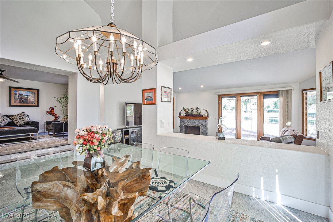 7772 Boca Raton Drive Las Vegas, NV 89113 - Photo 16 of 40 Dining space with a fireplace, recessed lighting, a ceiling fan, a high ceiling, and a chandelier